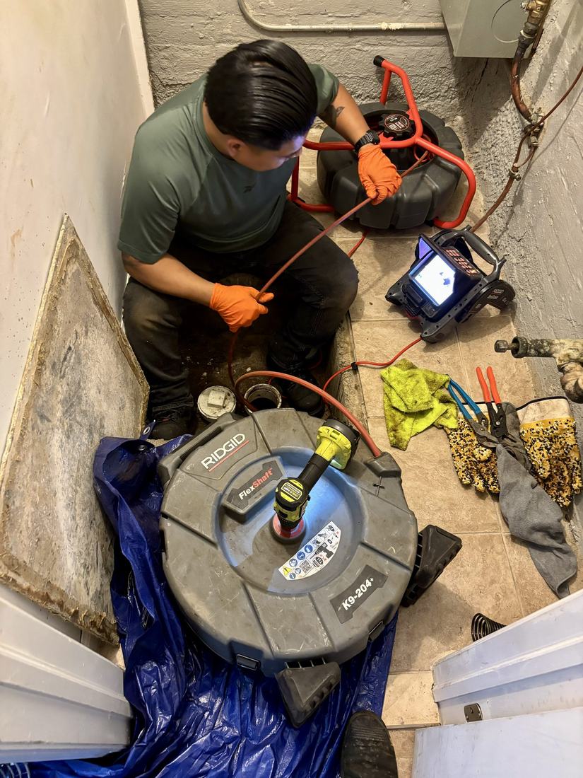 Technician clearing a drain line with a professional cable machine