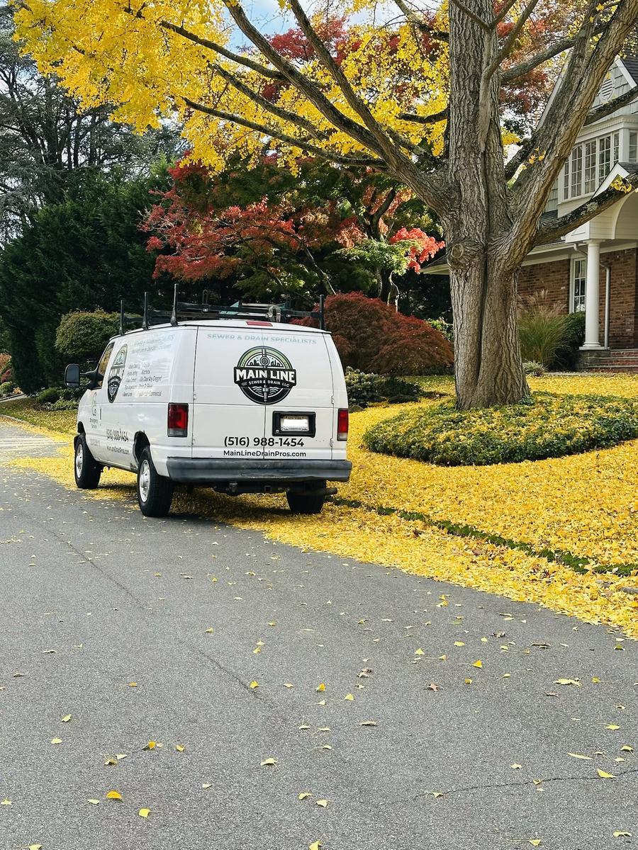 Main Line Sewer & Drain branded van parked on a leafy residential street in the Bellmore area